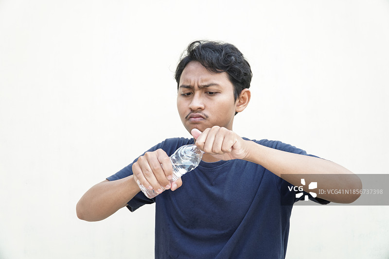 亚洲年轻男子费力地打开瓶盖图片素材