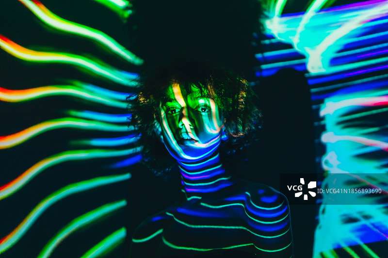在黑暗中的女人肖像，霓虹灯投射在女人身上。未来、预测和人工智能的概念图片素材