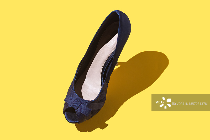 黄色背景上的蓝色绒面露趾高跟鞋图片素材
