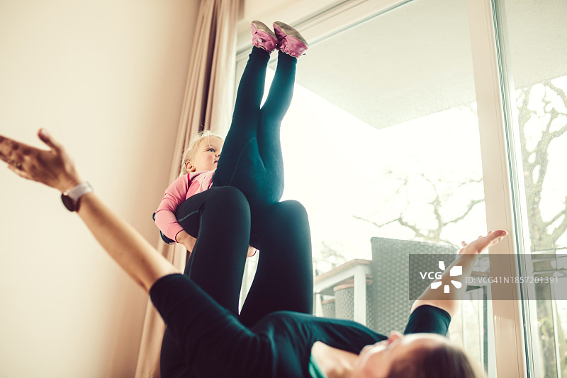 母亲在家运动时托举女儿图片素材