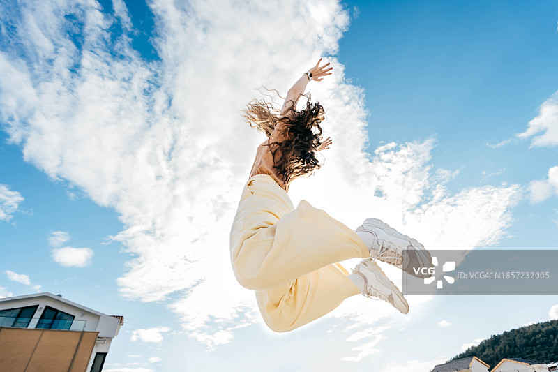 长发年轻女子纵身一跃，拥抱自由与快乐图片素材