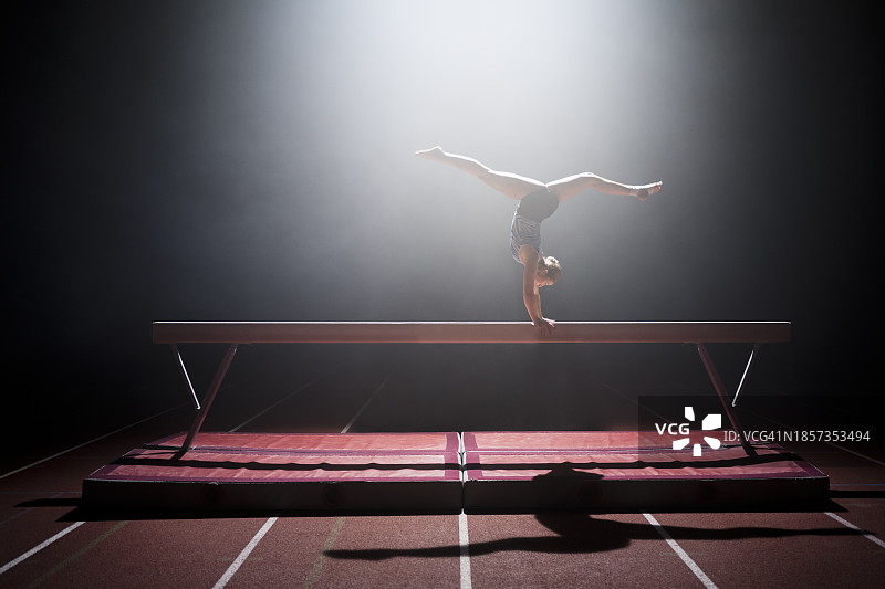 在平衡木上表演的体操女运动员图片素材