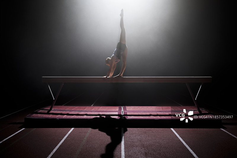 在平衡木上表演的体操女运动员图片素材