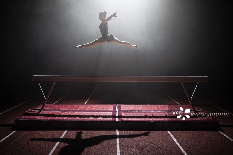 在平衡木上表演的体操女运动员图片素材