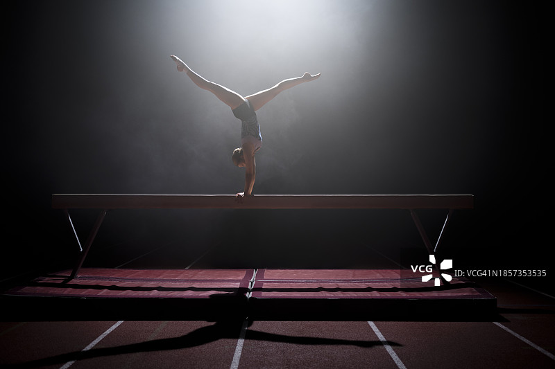 在平衡木上表演的体操女运动员图片素材