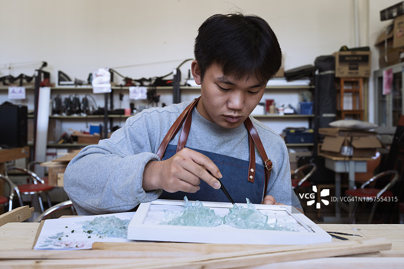 年轻男人用碎玻璃制作工艺品图片素材