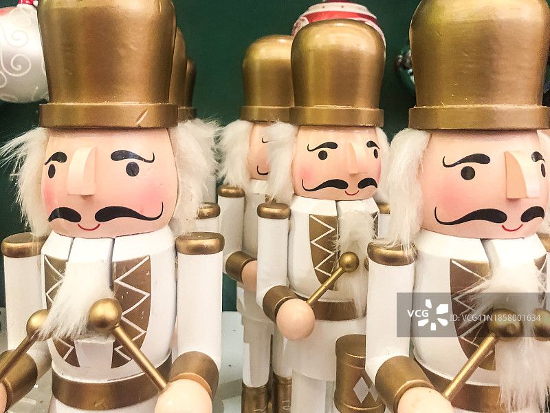 一排身穿白色西装、头戴金色帽子的胡桃夹子士兵。装饰、圣诞节、庆典、士兵、军事概念图片素材