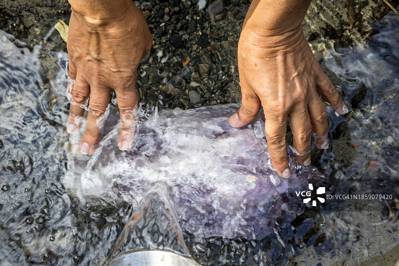 女人在泉边清洁大型紫水晶图片素材
