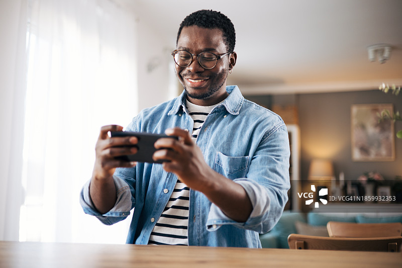 兴奋地用智能手机玩手机游戏的年轻黑人男子图片素材