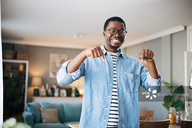 惊讶的黑人男子站着，向下指着食指图片素材