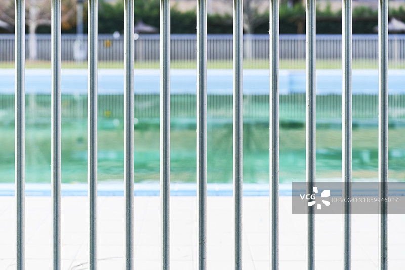 阳光明媚的日子里游泳池的金属栅栏的正面照，周围没有人图片素材