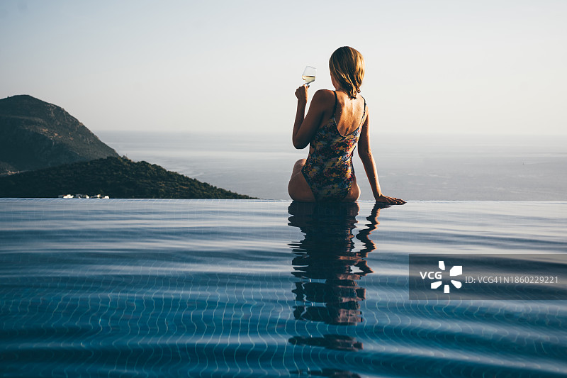 女人在无边泳池欣赏美景喝红酒图片素材
