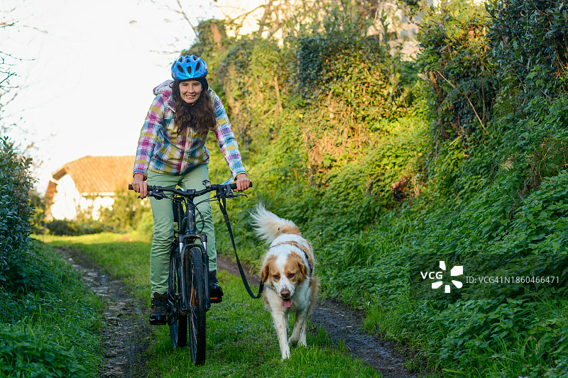 女子骑自行车训练小狗图片素材