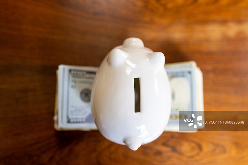 堆叠美元纸币上的白色小猪储蓄罐图片素材