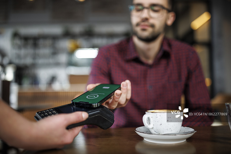 年轻男子在咖啡馆为订单付款图片素材