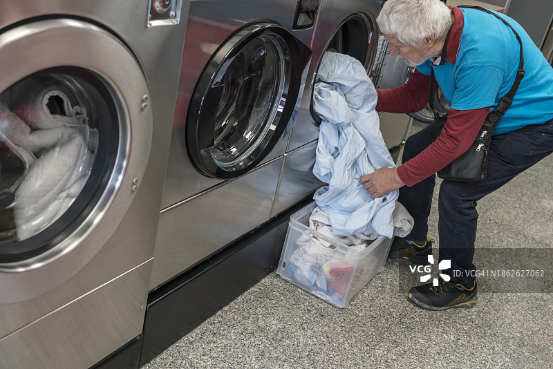 在公共洗衣店使用洗衣机的老年男人图片素材