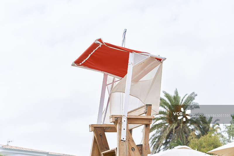 阳光明媚的海滩上，空救生椅和遮阳伞的侧面照图片素材