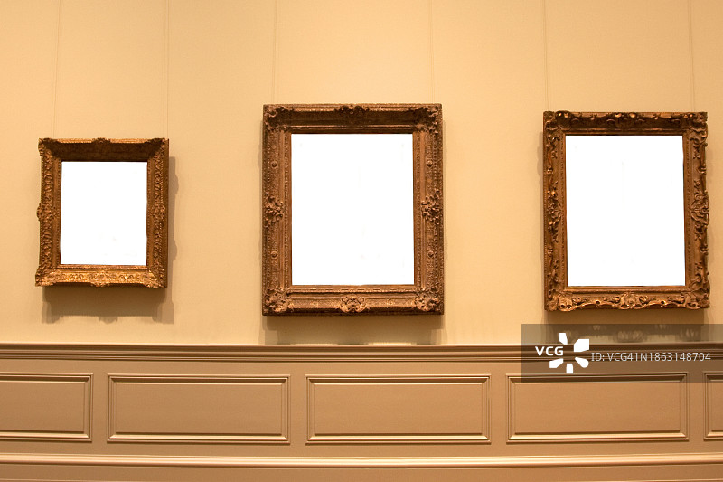 墙上悬挂的3个金色相框图片素材