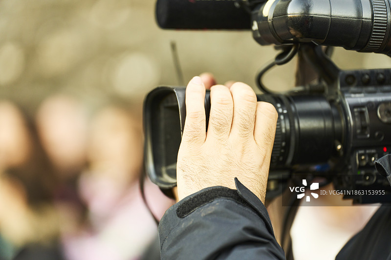 站立的人在街上手持专业数码相机的侧视图图片素材