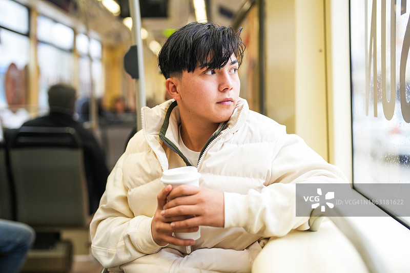 乘坐公共交通工具喝咖啡的年轻男人图片素材