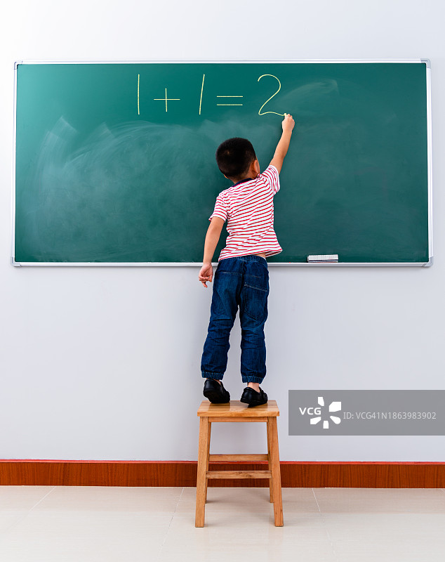 男孩在黑板上写1+1=2图片素材