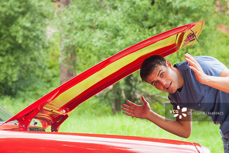 英俊的男人检查汽车引擎时迷路了图片素材