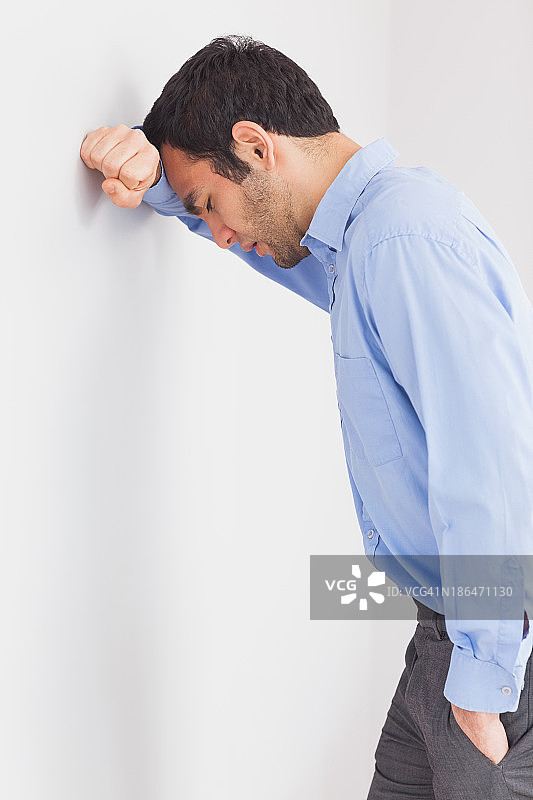 担忧的男人靠墙低头图片素材