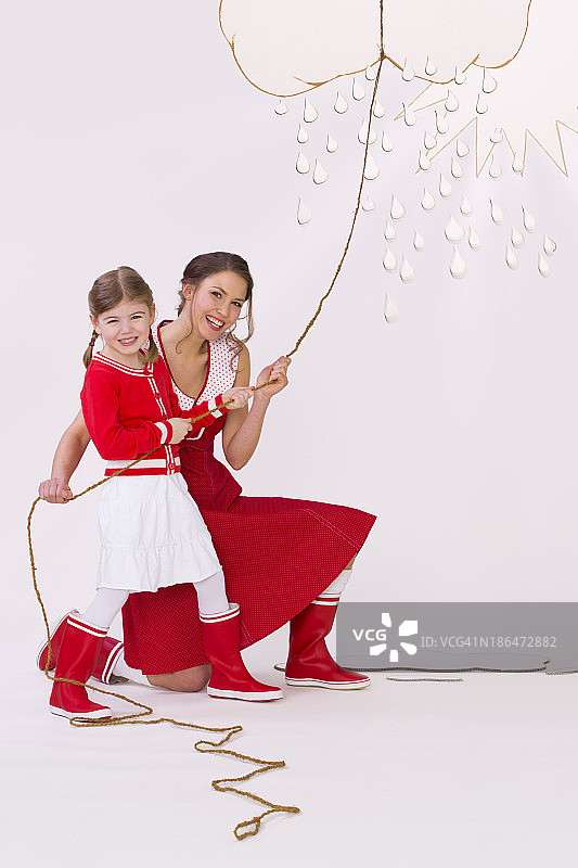 母女笑着拨开云、雨和阳光图片素材