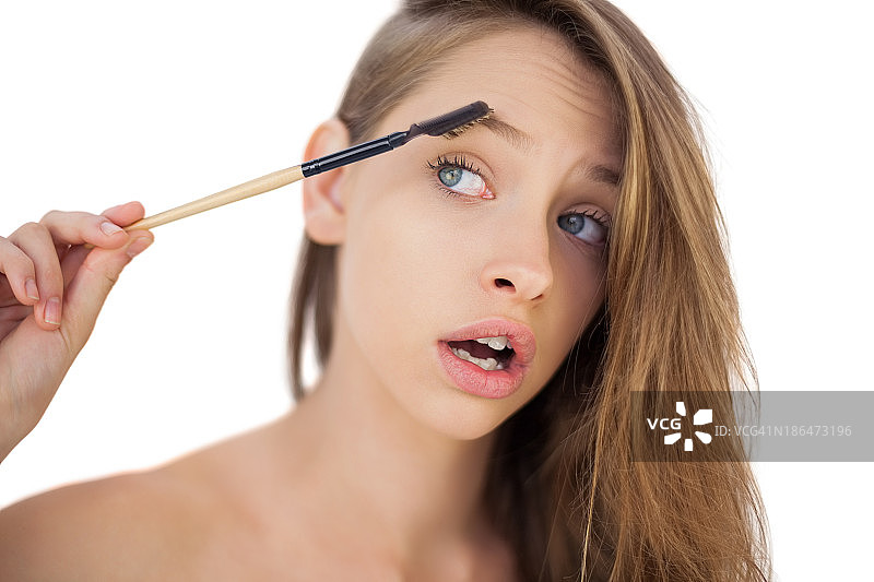 困惑的棕发女人刷眉毛图片素材