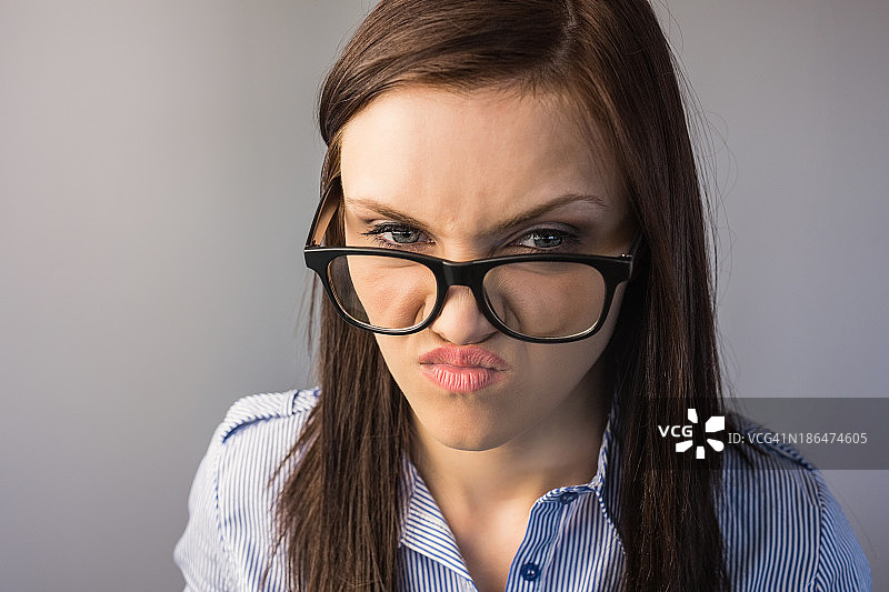 戴眼镜的严肃深色头发女子做鬼脸图片素材
