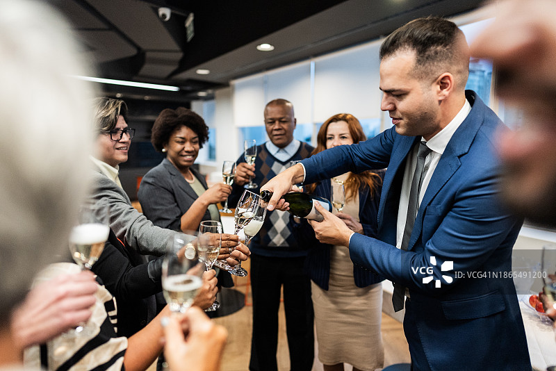 庆祝期间，经理在办公室为同事倒酒图片素材