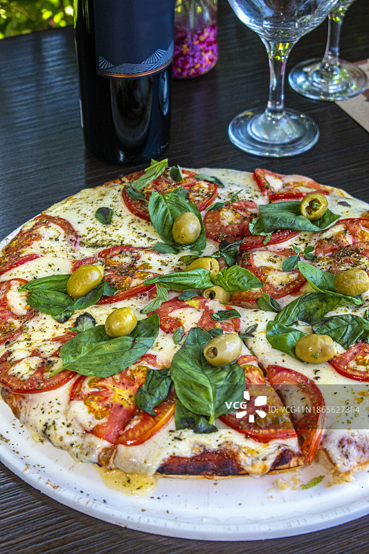 那不勒斯披萨，配马苏里拉奶酪、番茄、橄榄和罗勒或芝麻菜叶图片素材