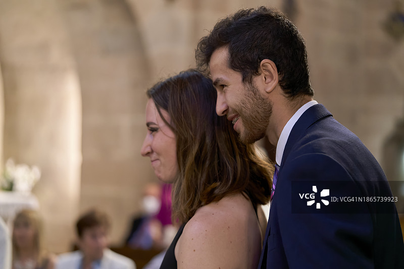 穿着考究的年轻夫妇在教堂里拥抱微笑的侧视图图片素材