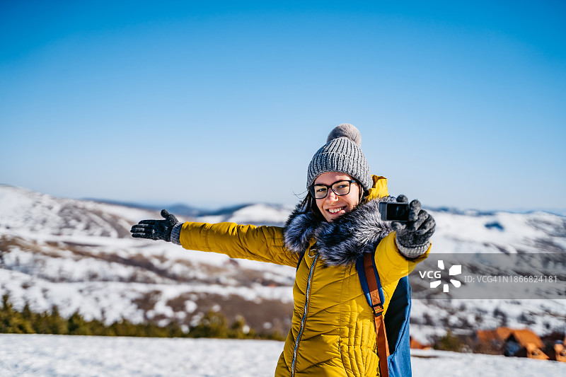 年轻女子在雪山上用GoPro自拍图片素材