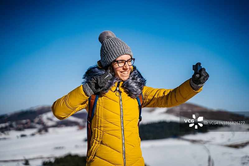 年轻女子在雪山上用GoPro自拍图片素材