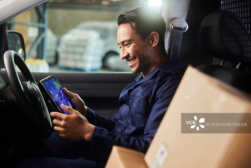 快递员坐在仓库的货车里使用平板电脑图片素材