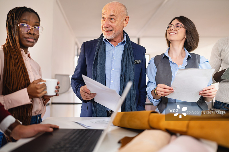 带领一群时装设计专业学生的年长男性纺织厂老板图片素材