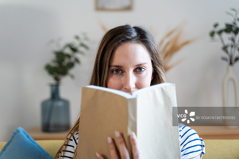 年轻女人在家中沙发上读书图片素材