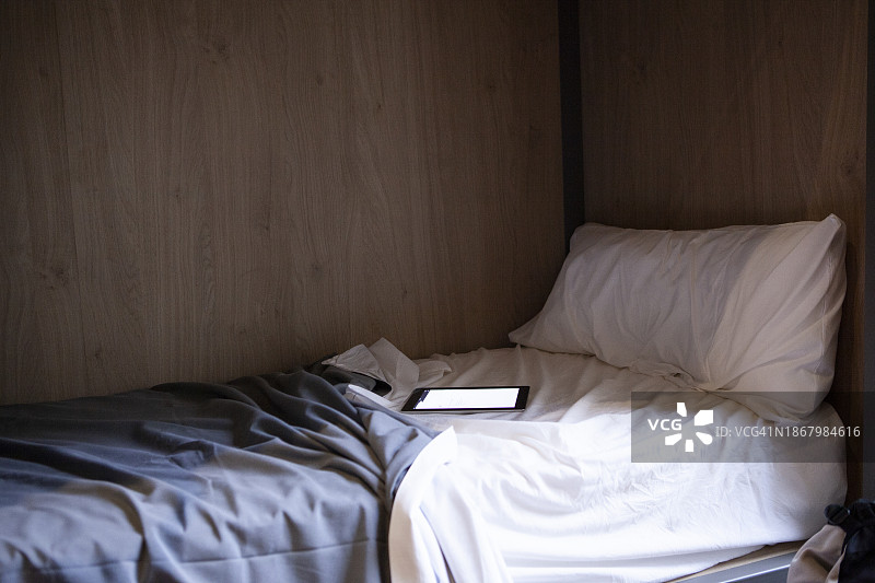 凌乱床铺上的开机平板电脑图片素材