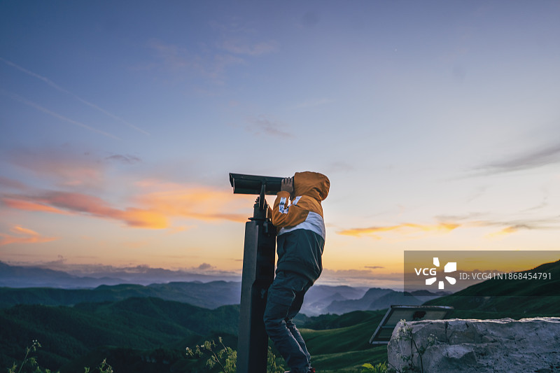 小男孩在户外使用双筒望远镜观察图片素材