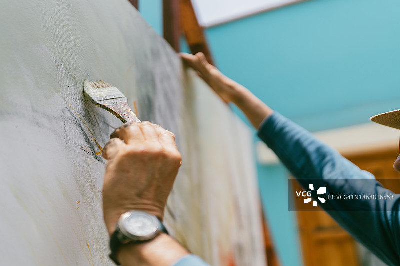 男人用刷子在巨大的画布上绘画图片素材