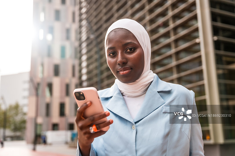 非洲裔穆斯林女商人在金融大厦外使用手机图片素材