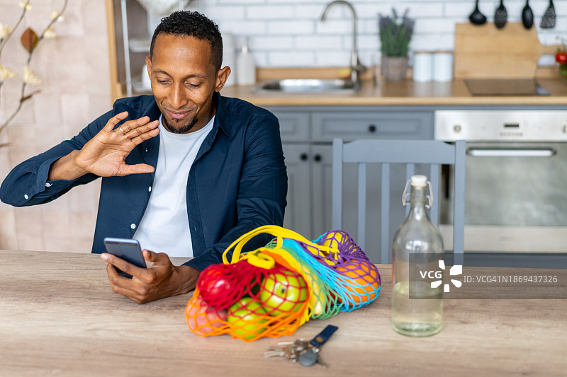 男人拿着购物袋向手机挥手图片素材