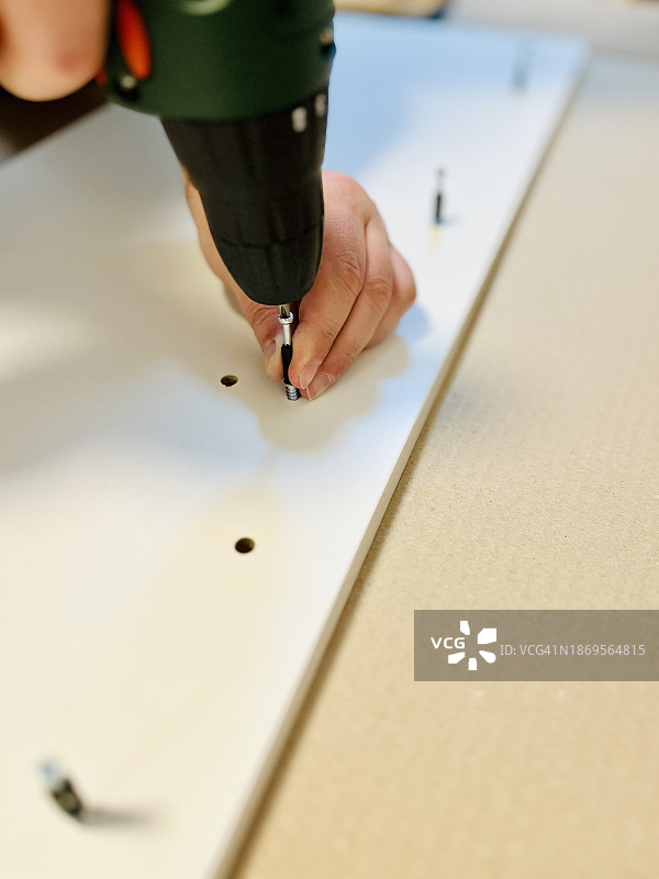 男人用电动螺丝刀组装家具的特写图片素材