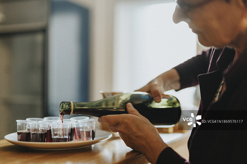 年长的女人在犹太教堂的犹太教集会上倒酒图片素材