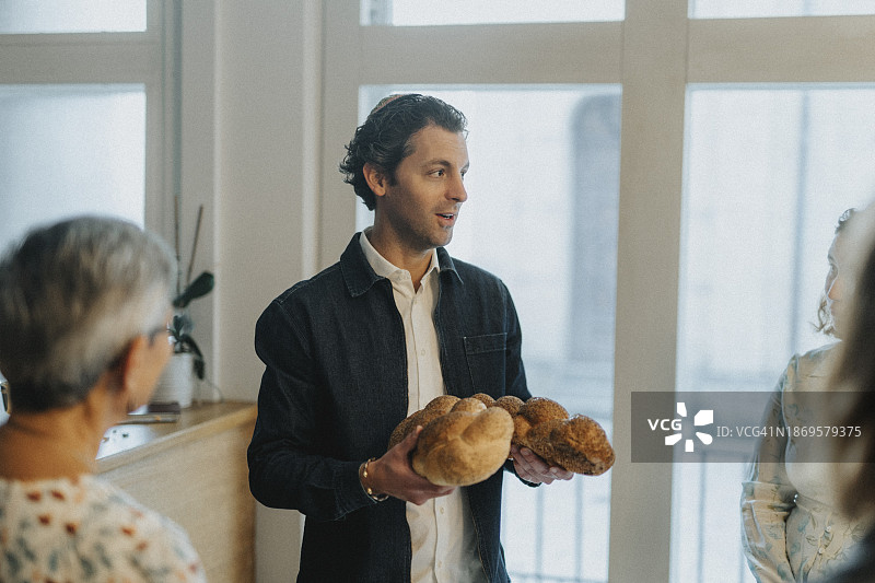 犹太男子在犹太教堂会众期间手持哈拉面包与人交谈图片素材