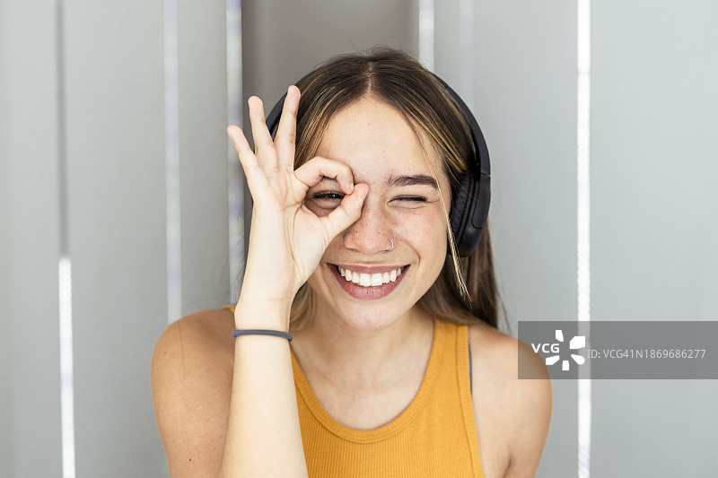在家中用手势在脸上比OK的快乐女人图片素材
