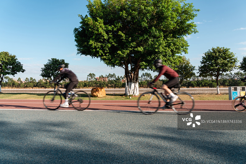 公园自行车道上人们骑自行车的模糊动感图片素材