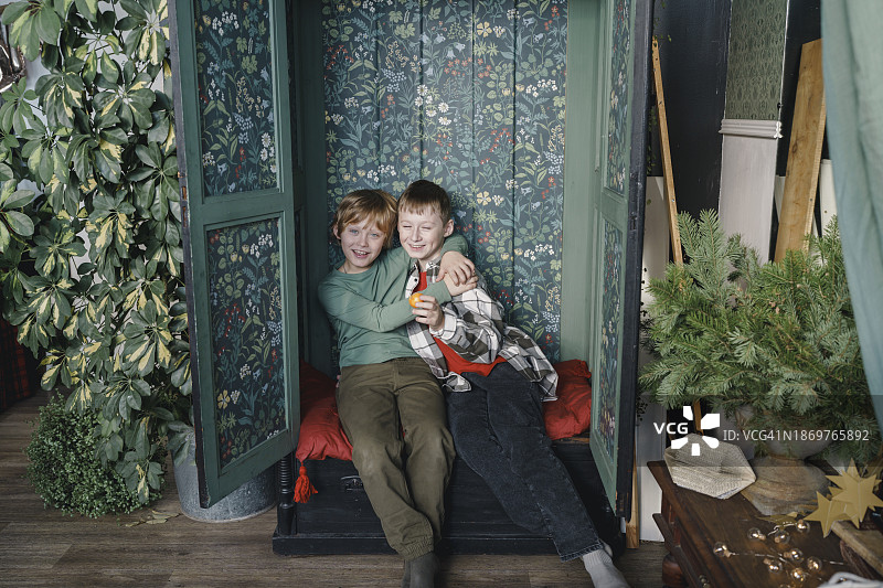 微笑的男孩们坐在家里的壁橱里图片素材