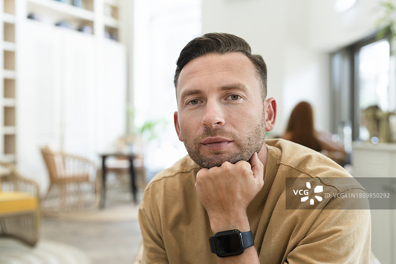手托下巴坐在家里的自信男人图片素材